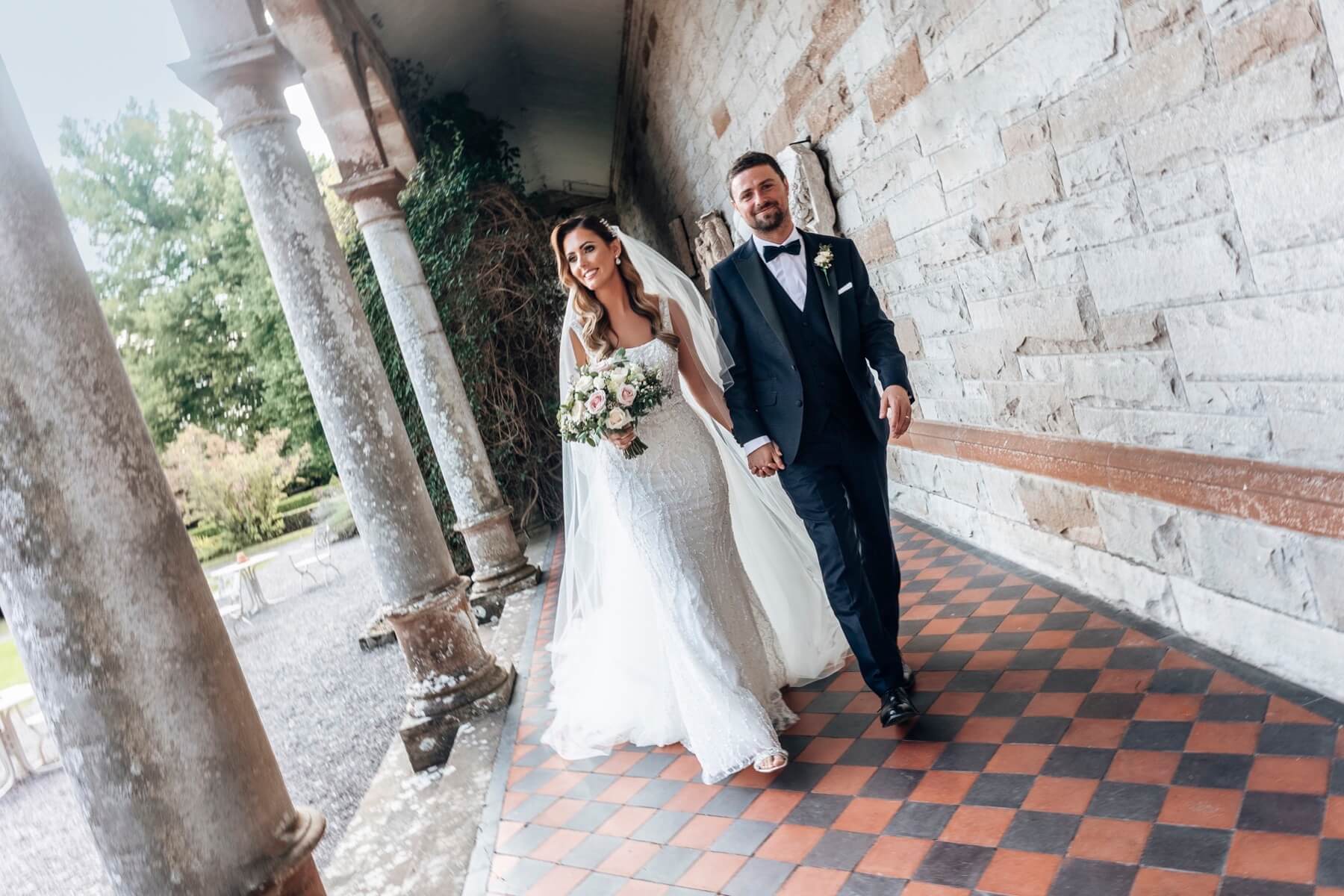 Couple walking through the archways at Castle Leslie