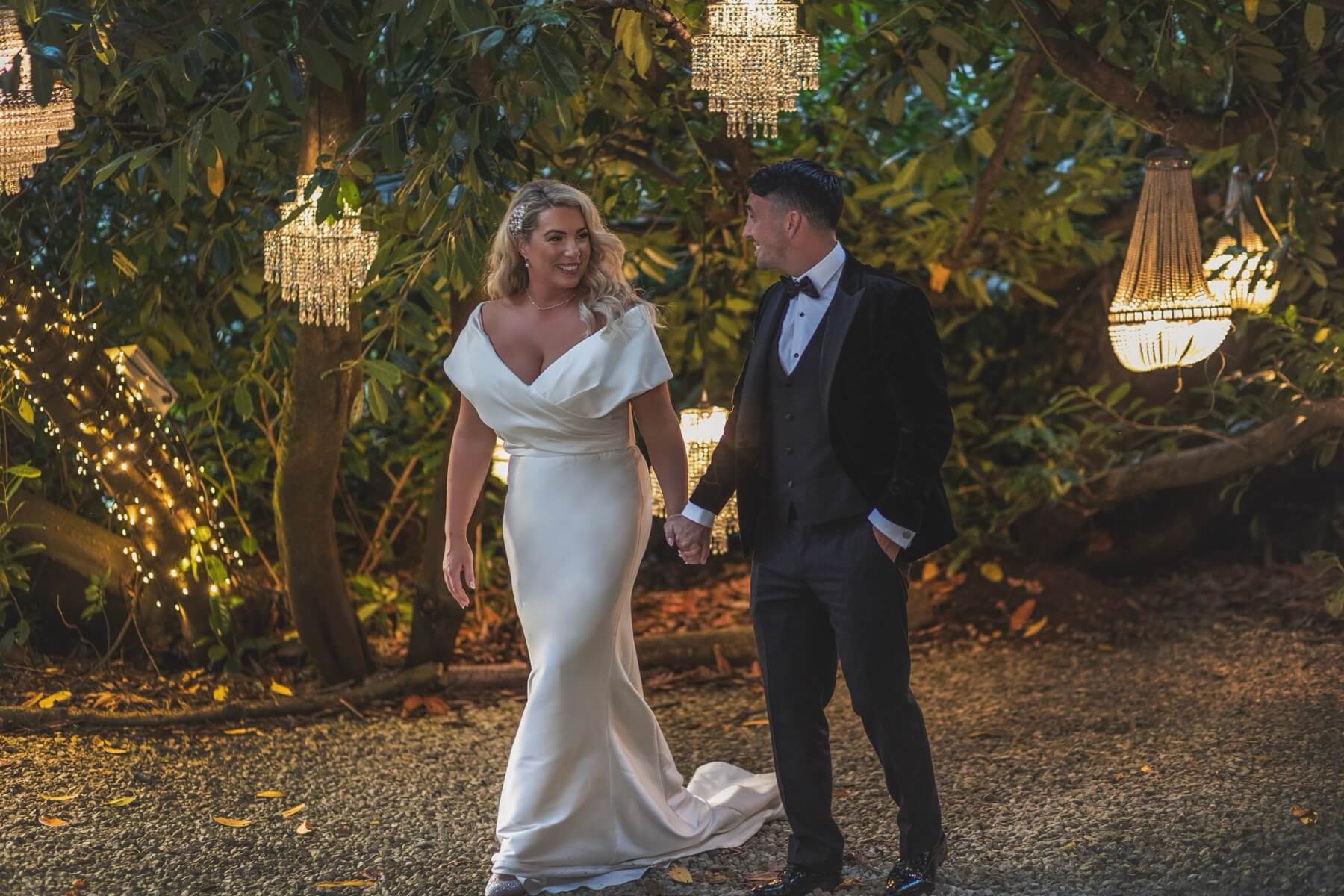 Wedding couple under chandelier-lit trees Galgorm evening
